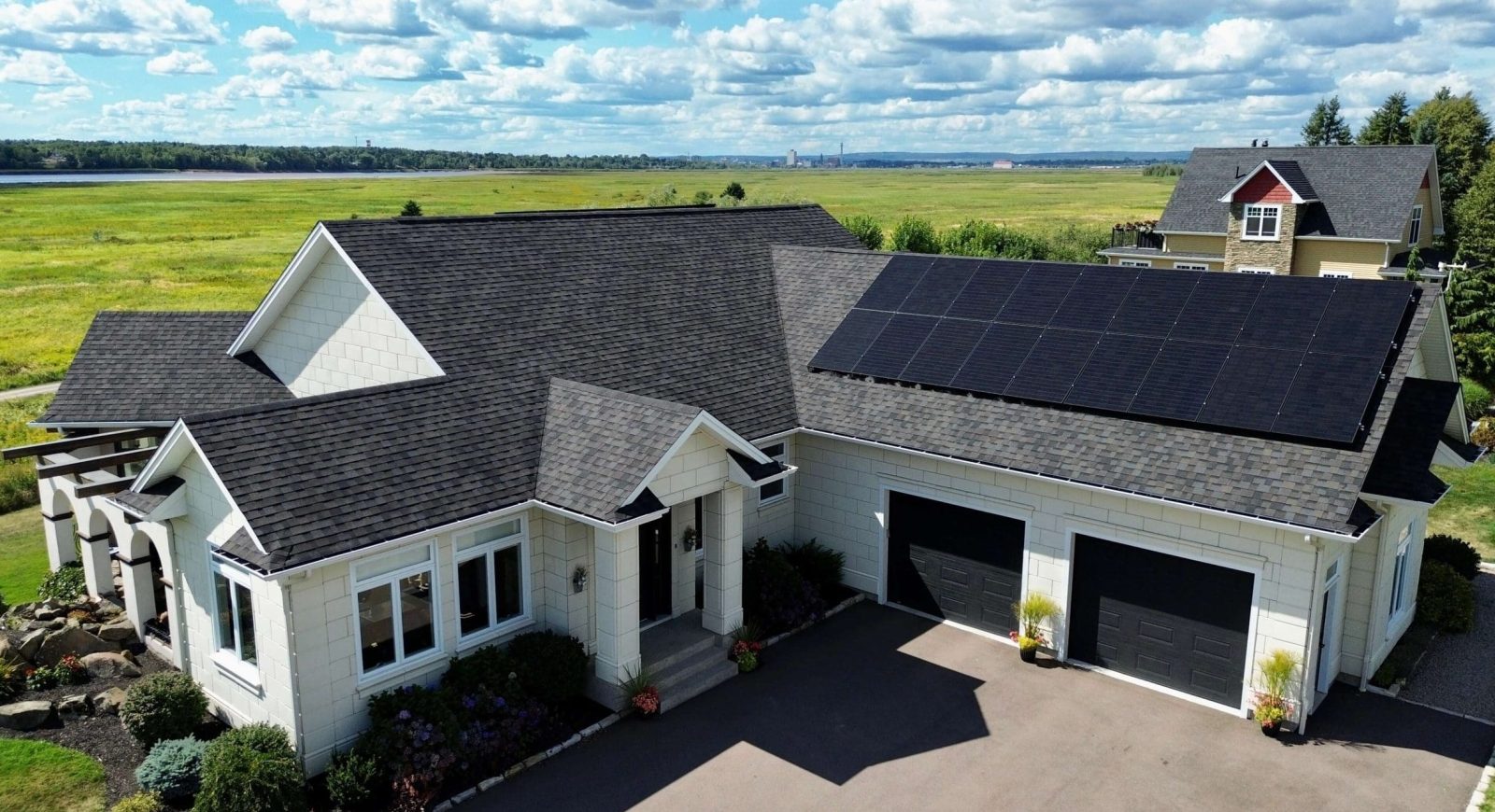 Image of a house with a asphalt shingle roof and black solar panels on it in New Brunswick