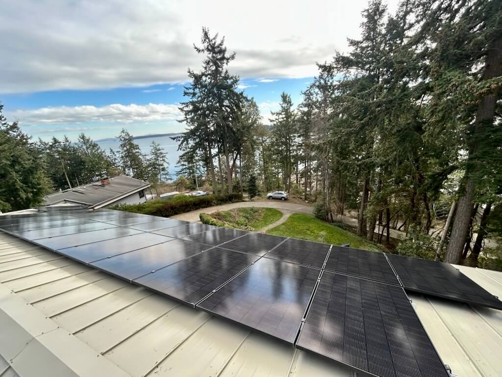 Image of a house with a metal roof and black solar panels on it in BC