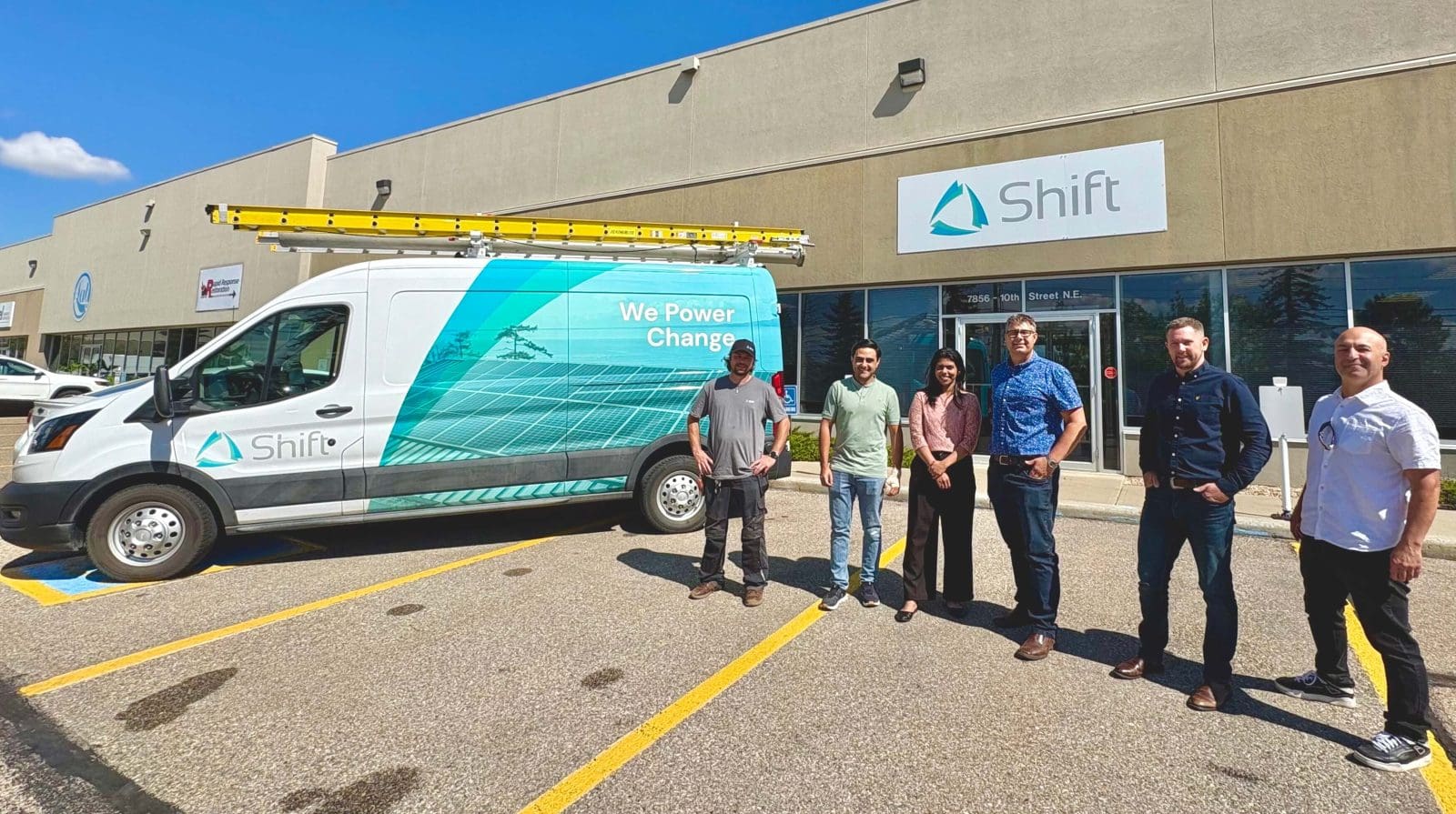 Calgary Shift team standing beside a Shift van in front of the Shift office