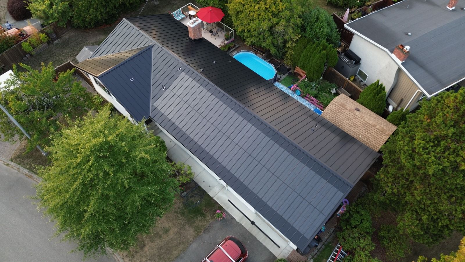 Aerial view of a home with BIPV solar panels. The panels blend seamlessly into the black metal roof.