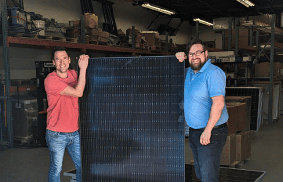 Team member Chris posing with a solar panel with a client. The panels are being donated to our client, to be upcycled and used on his farm.